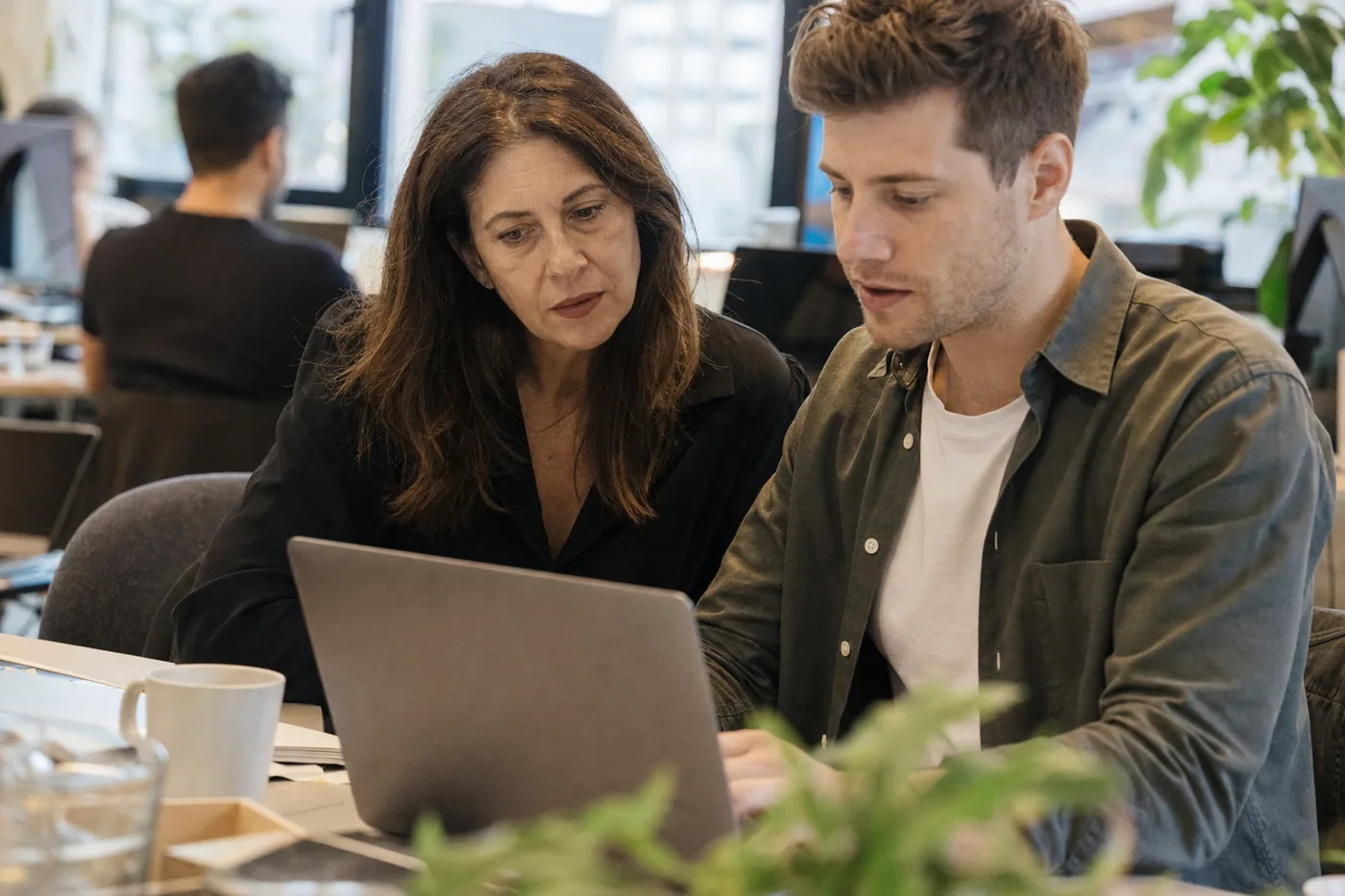 A hiring manager and a new employee working through a real task together on a laptop, the human check against AI hiring fraud