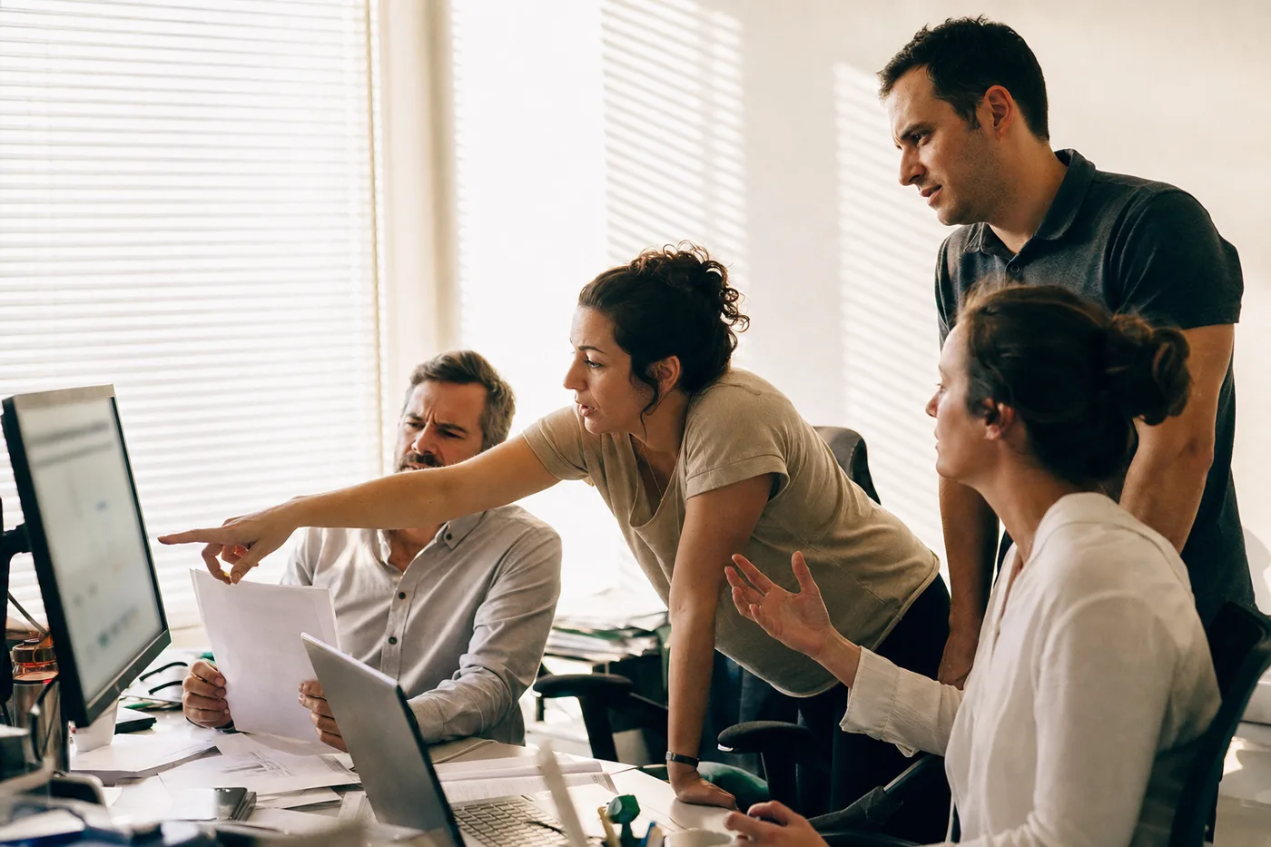 A team debating and questioning training content together around a shared screen instead of accepting it passively