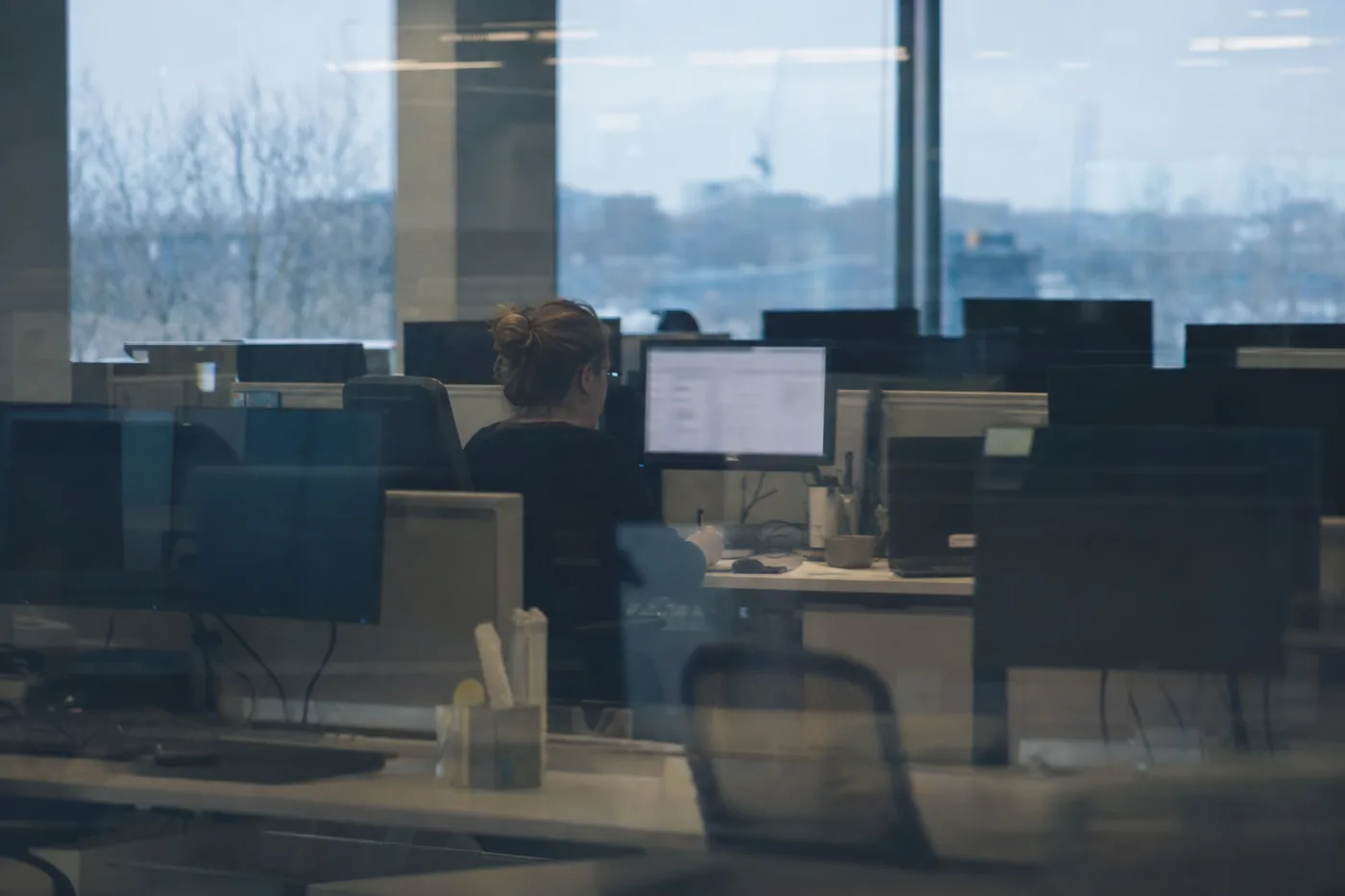 One engaged learner at her screen surrounded by empty desks with dark monitors, showing the gap between access and usage