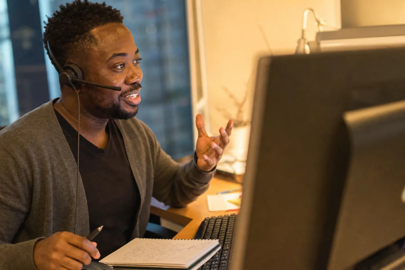 An employee with a headset talking back to an AI tutor on screen, caught mid-gesture in an interactive learning exchange