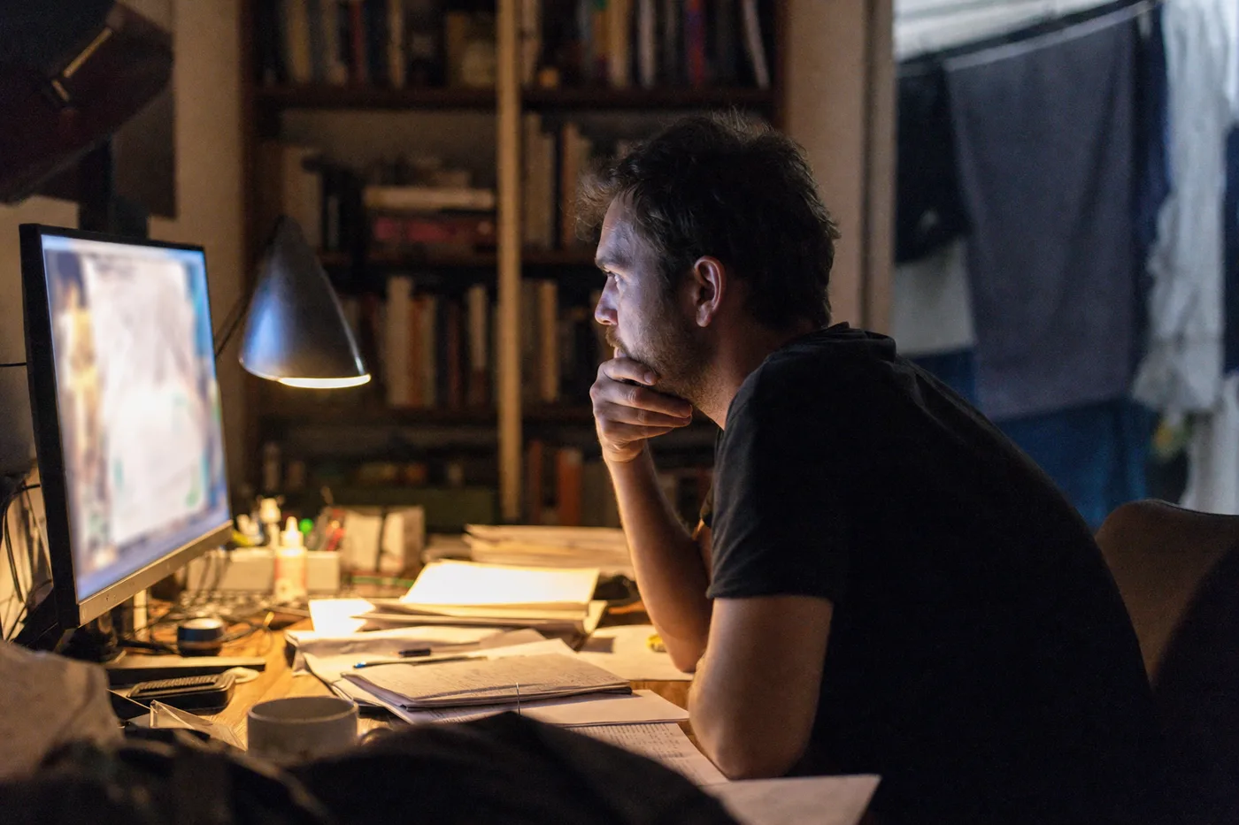 A learner leaning in to read personalized feedback from an AI tutor on his monitor at a home desk in the evening