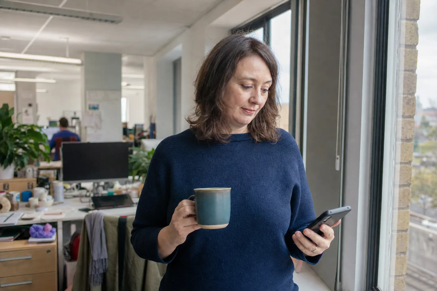 Office worker completing a short microlearning lesson on a phone during a coffee break between meetings