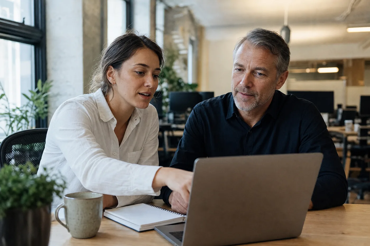 Two coworkers reviewing a personalized corporate training plan together at a laptop in a bright office