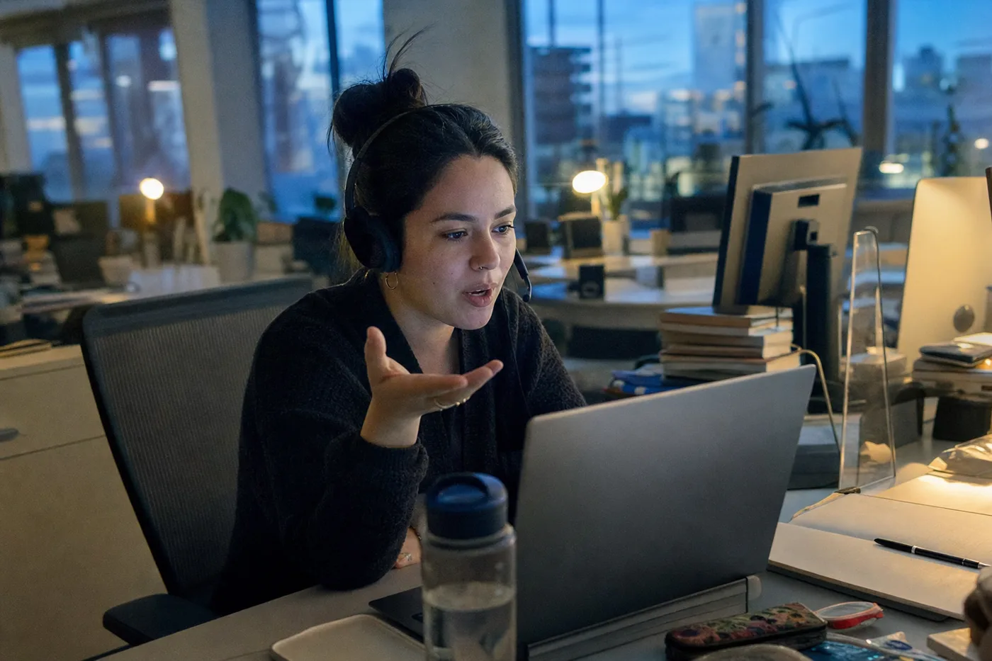 Employee practicing a mock conversation with a headset at an evening workstation
