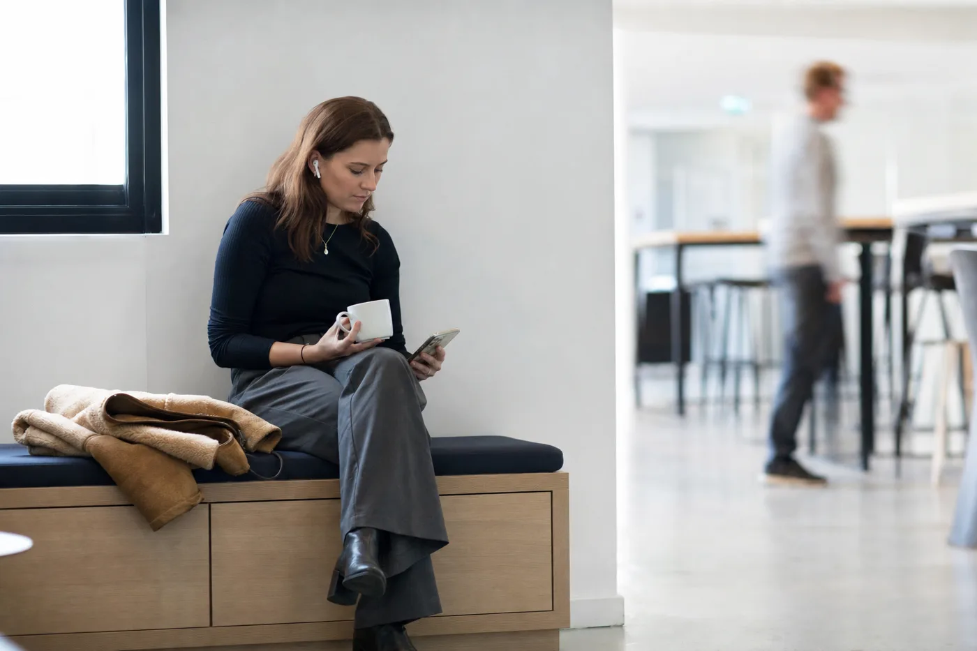 An employee doing a short workplace microlearning lesson on her phone during a coffee break